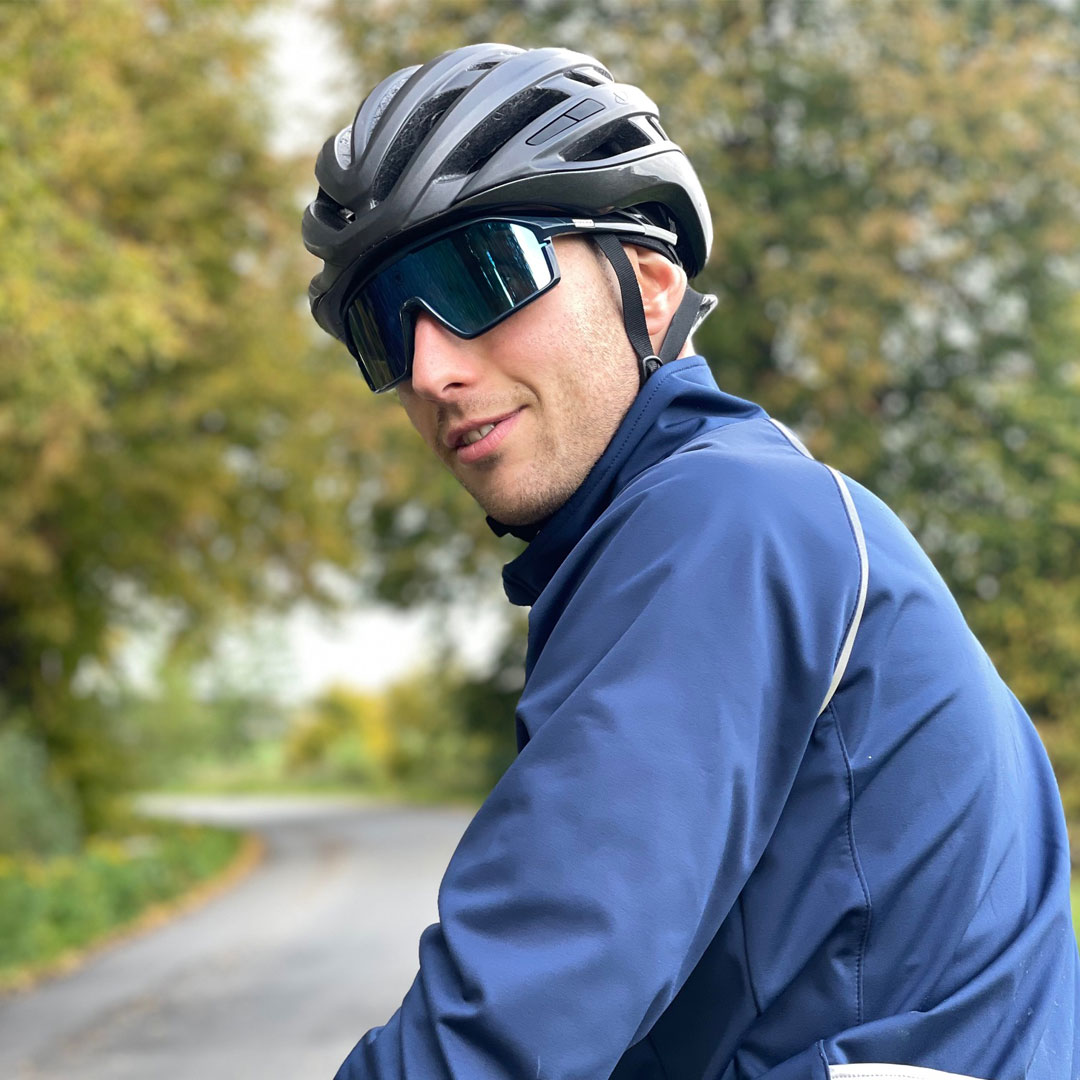 A male cyclist is smiling and turning back